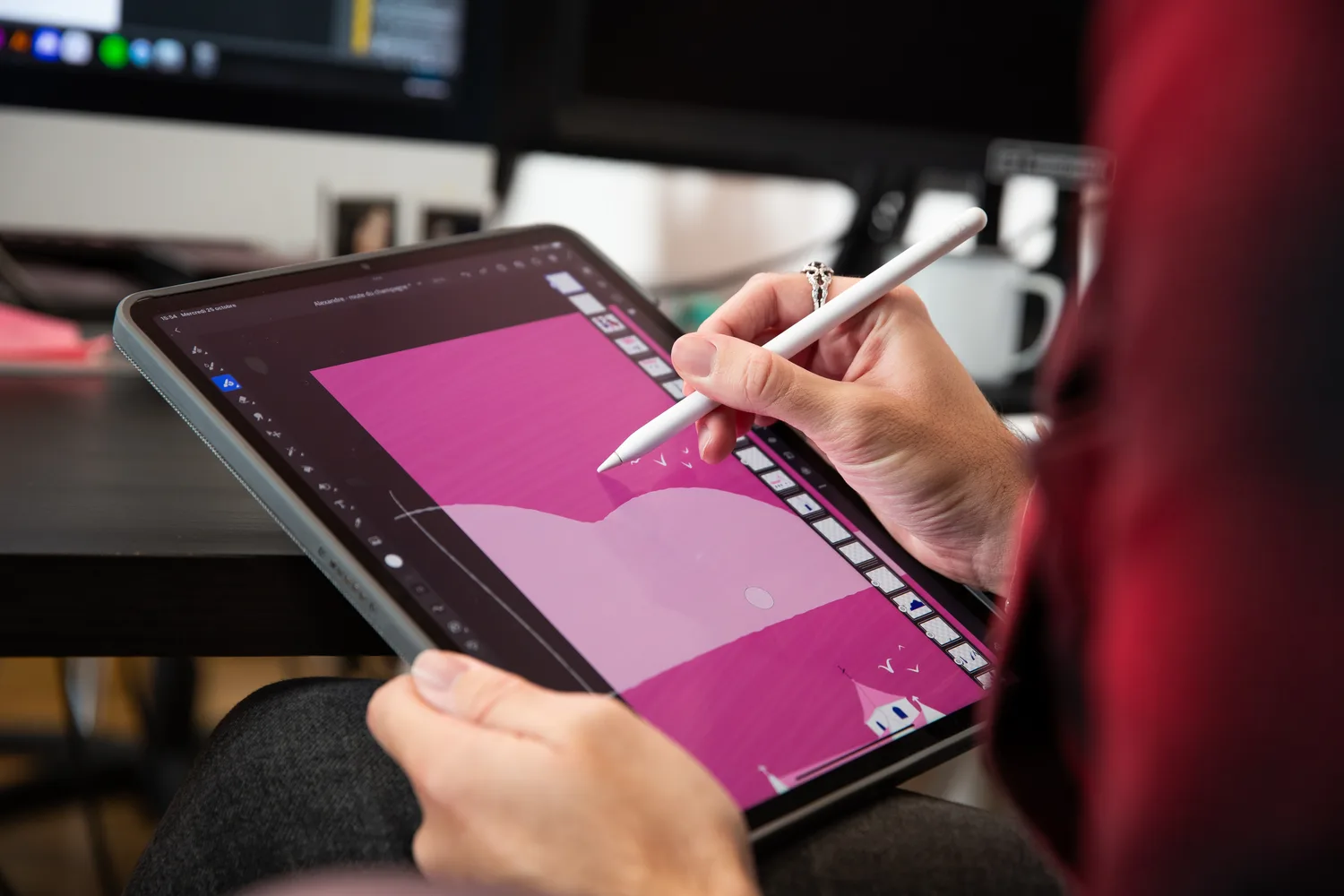 Une illustratrice dessine au stylet sur une tablette, dans les bureaux de l'agence.