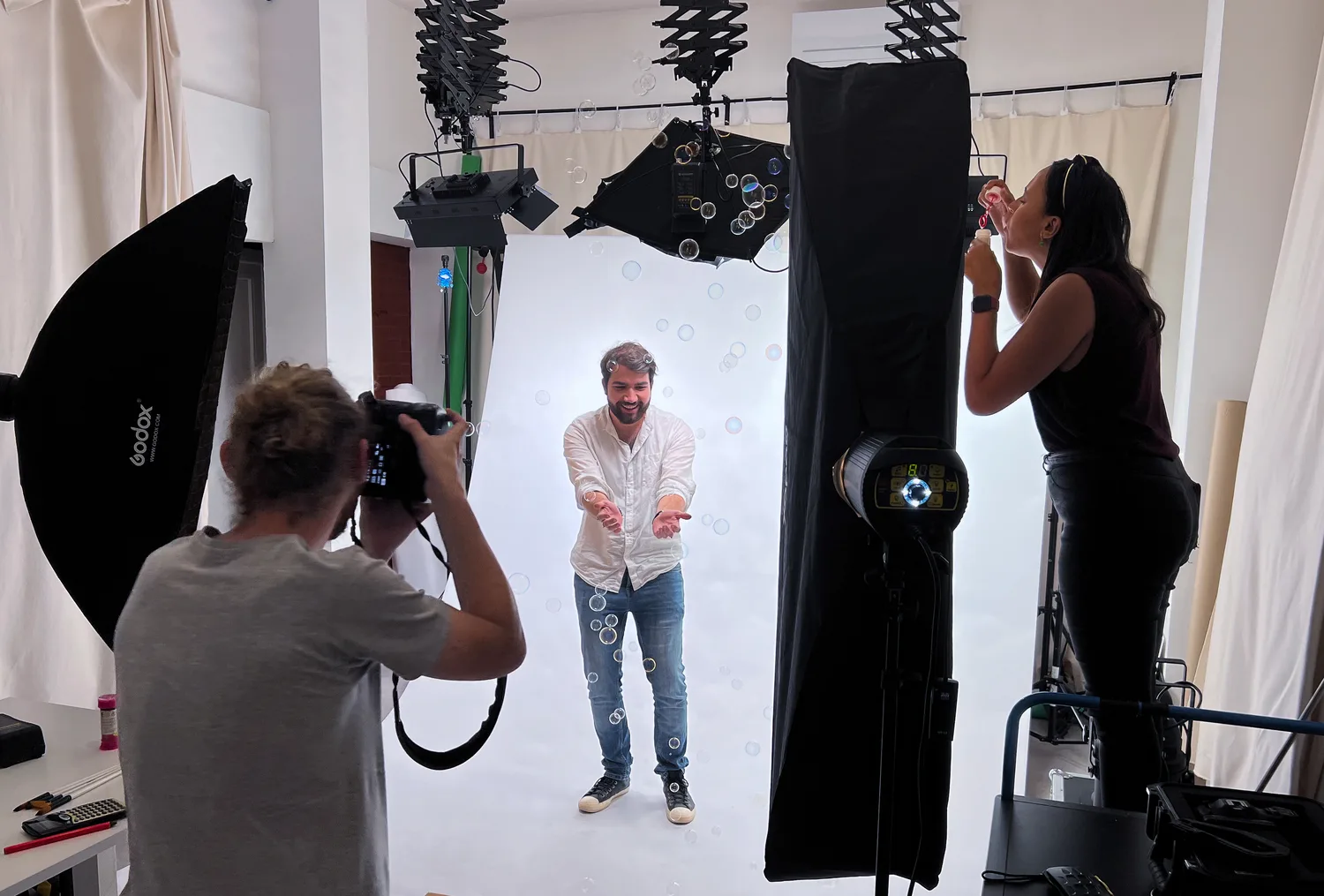 Une séance photo au studio de l'agence : un photographe cadre un homme en chemise blanche, sous les éclairages.