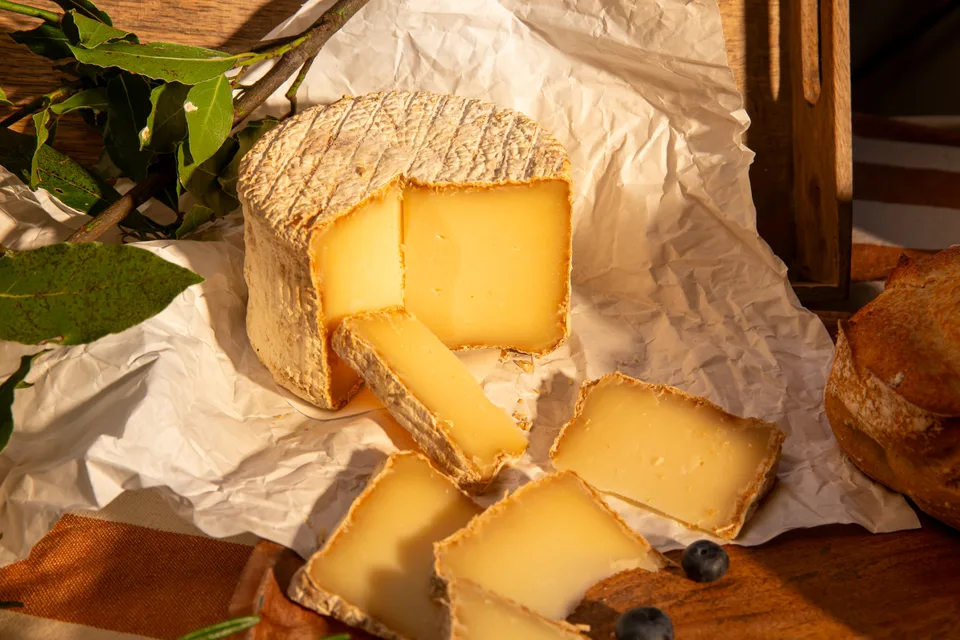 Une meule de fromage entamée sur un papier froissé.