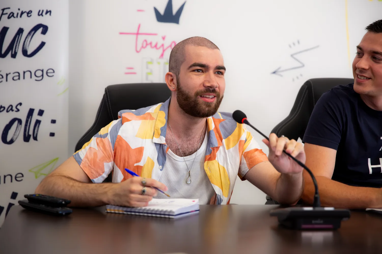 Deux membres de l'équipe Zetruc attablés devant leurs micros, l'un prend des notes en écoutant.