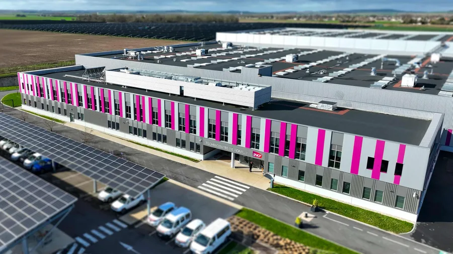 Le Technicentre SNCF de Romilly vu du ciel, un long bâtiment gris et rose entouré de champs et d’ombrières solaires.