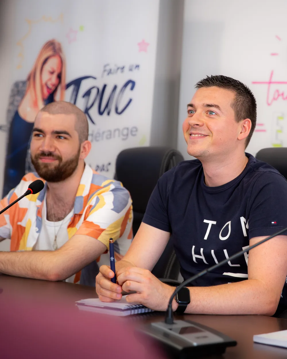 Deux membres de l'équipe Zetruc souriants, attablés devant leurs micros pendant une séance.