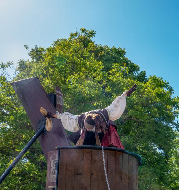 Un pirate perché sur son décor, bras écartés, pendant le spectacle de pirates de Grinyland.