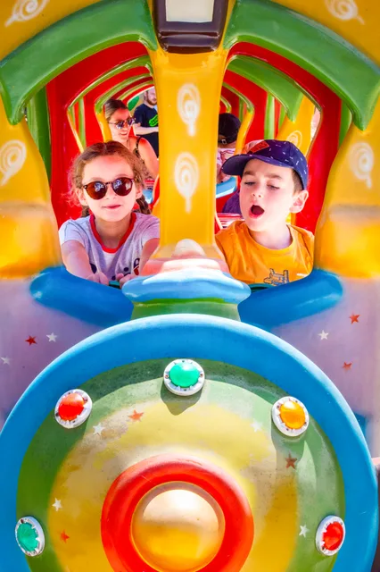 Deux enfants rient aux éclats à bord du petit train coloré de Grinyland.