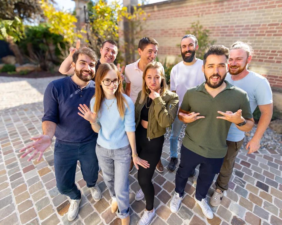 L'équipe Zetruc réunie dans la cour de l'agence, tout sourire, qui montre l'objectif du doigt.