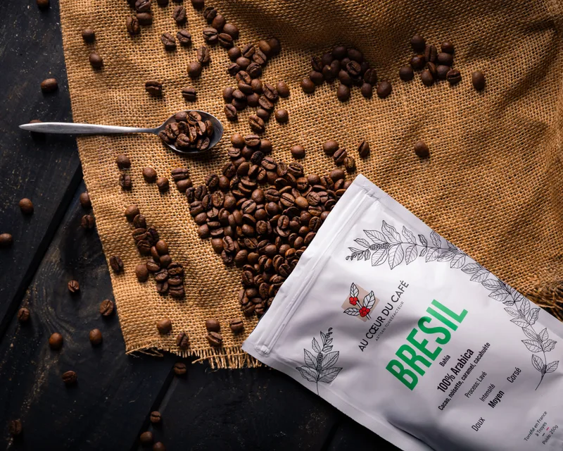 Un sachet de café « Brésil » ouvert sur une toile de jute, grains de café éparpillés.