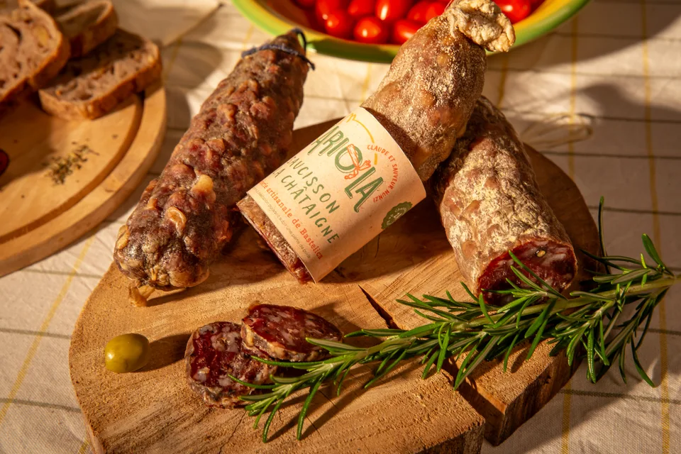 Un saucisson tranché sur une planche, avec romarin et tomates cerises.