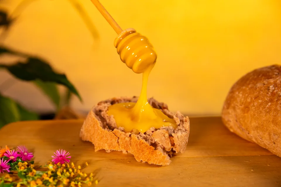 Le miel coule d'une cuillère à miel sur une tartine de pain.